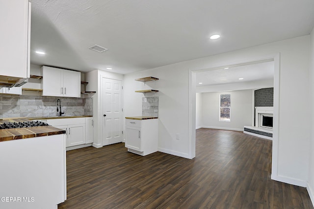 kitchen with dark wood finished floors, butcher block counters, open shelves, backsplash, and visible vents