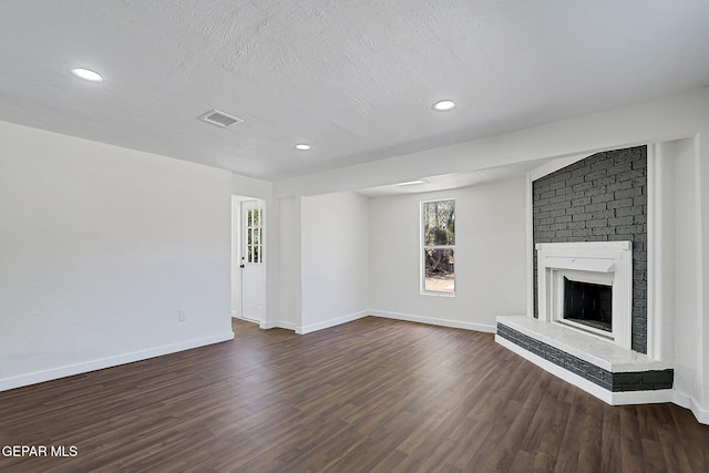 unfurnished living room featuring recessed lighting, a brick fireplace, baseboards, visible vents, and dark wood-type flooring