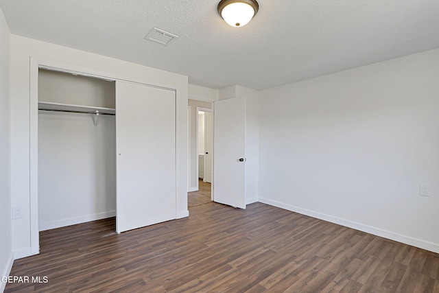 unfurnished bedroom featuring baseboards, visible vents, dark wood-style flooring, and a closet