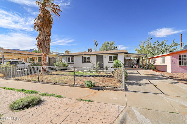 single story home with concrete driveway, a carport, a fenced front yard, and stucco siding