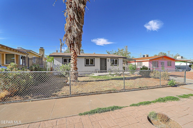 ranch-style home featuring stucco siding and a fenced front yard