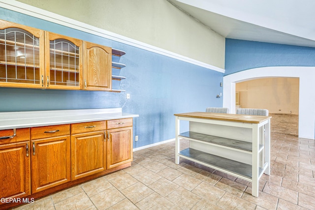 11144 Perlette St, Socorro, TX 79927 - kitchen with glass insert cabinets, open shelves, brown cabinetry, light countertops, and arched walkways