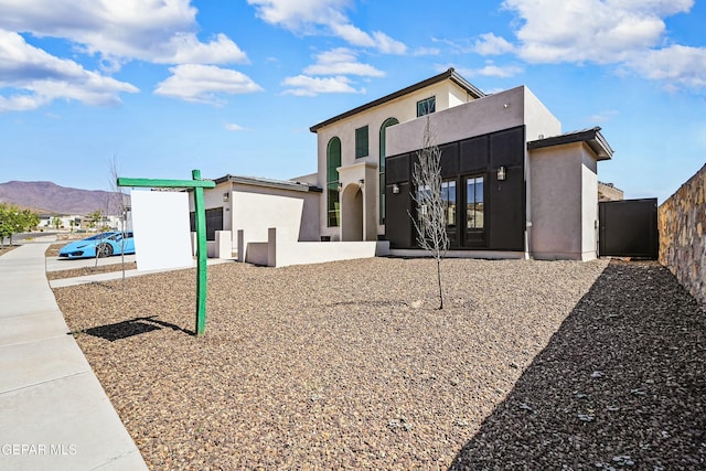 rear view of property featuring stucco siding, fence, and a mountain view