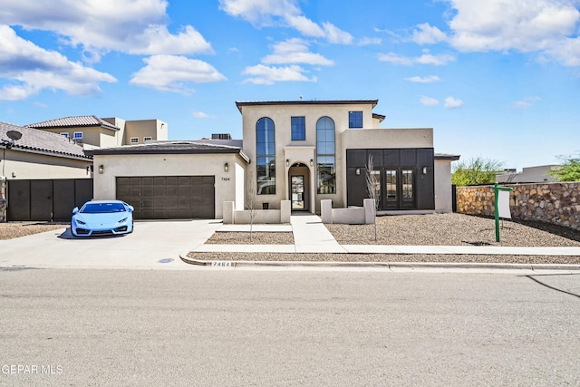 view of front of property featuring a garage, concrete driveway, stucco siding, french doors, and fence