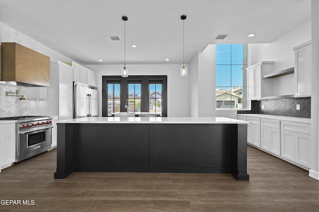 kitchen with premium appliances, wall chimney exhaust hood, open shelves, and backsplash