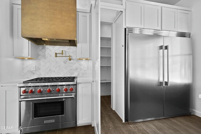 kitchen with light countertops, high quality appliances, white cabinetry, and dark wood-type flooring
