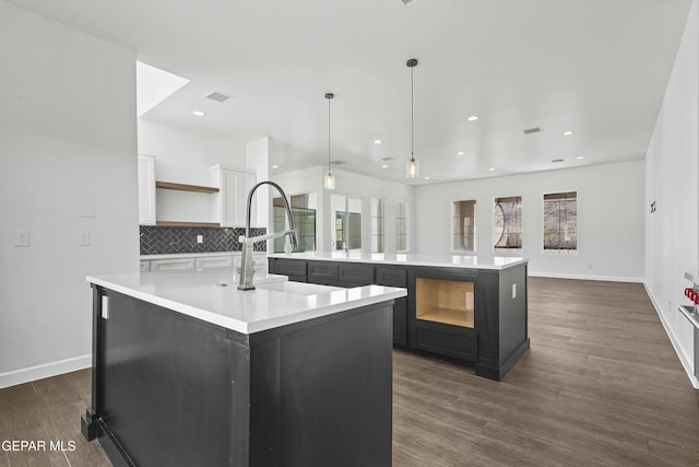 kitchen with decorative backsplash, a large island with sink, open shelves, and light countertops