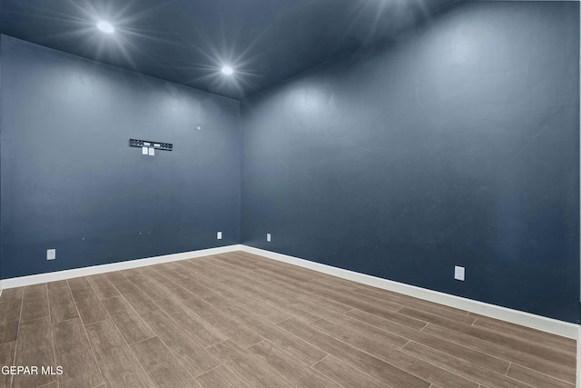 empty room with baseboards, recessed lighting, and wood finished floors