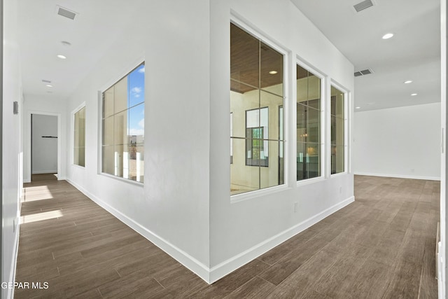 hall featuring wood finished floors, visible vents, and baseboards