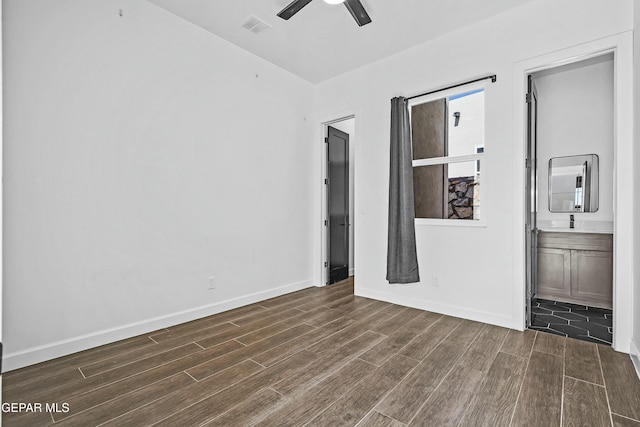 unfurnished bedroom with dark wood finished floors, visible vents, ensuite bathroom, and baseboards