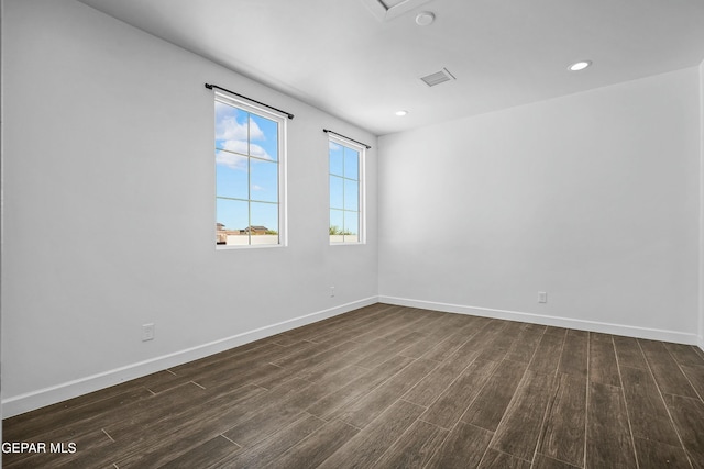 empty room featuring baseboards, visible vents, dark wood-type flooring, and recessed lighting