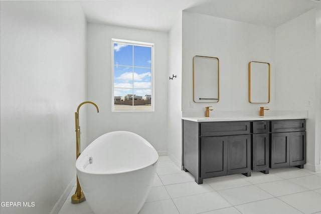 bathroom with double vanity, a freestanding tub, tile patterned flooring, and baseboards