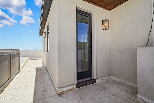 entrance to property featuring stucco siding and a balcony