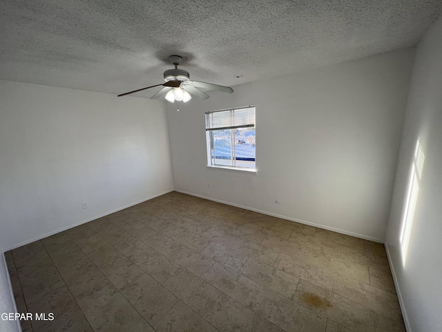 empty room featuring a textured ceiling, a ceiling fan, and baseboards