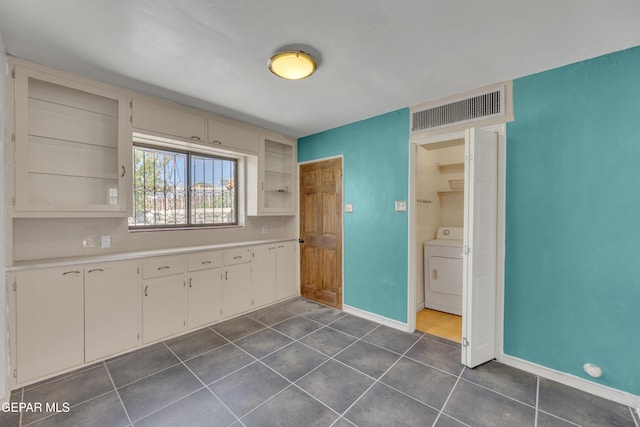 1003 Alethea Park Dr, El Paso, TX 79902 - kitchen with dark tile patterned floors, washer / clothes dryer, visible vents, light countertops, and baseboards