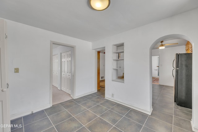 1003 Alethea Park Dr, El Paso, TX 79902 - spare room featuring ceiling fan, arched walkways, built in features, baseboards, and dark tile patterned floors