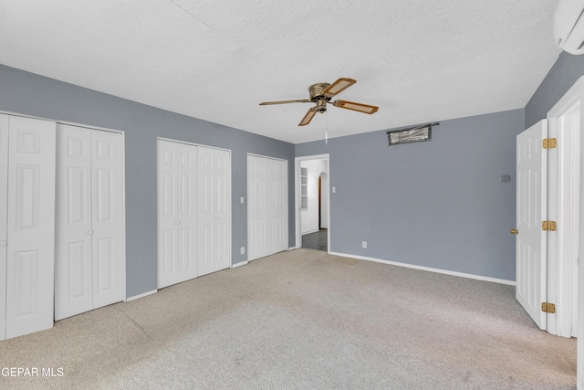 1003 Alethea Park Dr, El Paso, TX 79902 - unfurnished bedroom with carpet floors, two closets, baseboards, an AC wall unit, and a textured ceiling