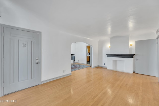 1003 Alethea Park Dr, El Paso, TX 79902 - unfurnished living room with arched walkways, baseboards, and light wood finished floors