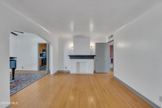 1003 Alethea Park Dr, El Paso, TX 79902 - unfurnished living room featuring arched walkways, baseboards, light wood finished floors, and visible vents