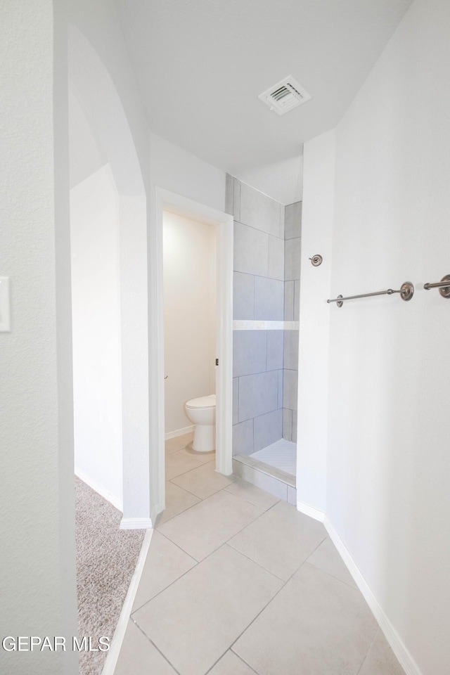 bathroom with visible vents, tile patterned flooring, toilet, baseboards, and a tile shower