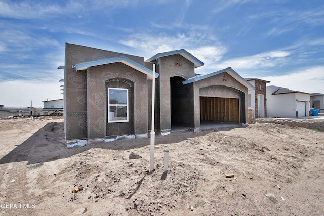 unfinished property featuring a garage and stucco siding