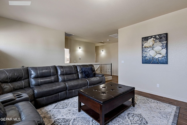 living room with baseboards, visible vents, and wood finished floors