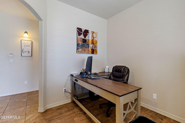 office space with wood finished floors, baseboards, and arched walkways