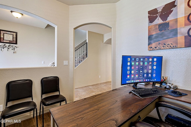 home office featuring arched walkways and tile patterned floors