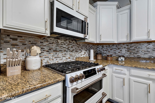 kitchen featuring light stone counters, white cabinetry, gas stove, white microwave, and backsplash