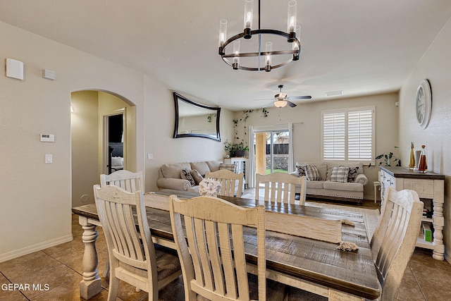 dining space with arched walkways, visible vents, baseboards, tile patterned flooring, and ceiling fan with notable chandelier