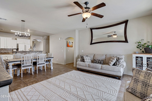 living room featuring tile patterned floors, visible vents, arched walkways, and ceiling fan