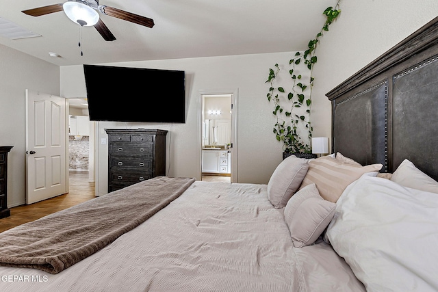 bedroom featuring wood finished floors, ceiling fan, and ensuite bath