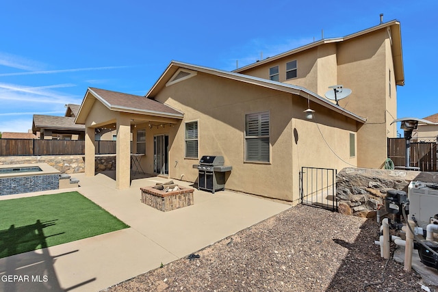 back of property with an outdoor fire pit, a fenced backyard, stucco siding, and a patio area