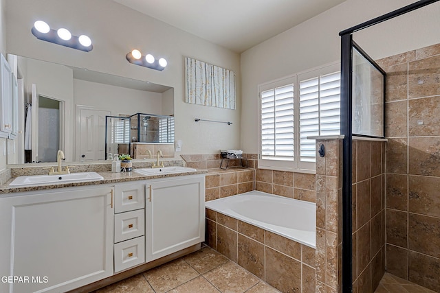 bathroom featuring a stall shower, double vanity, a sink, and a bath