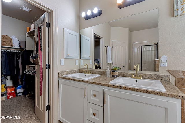 bathroom with visible vents, a shower stall, a spacious closet, and a sink