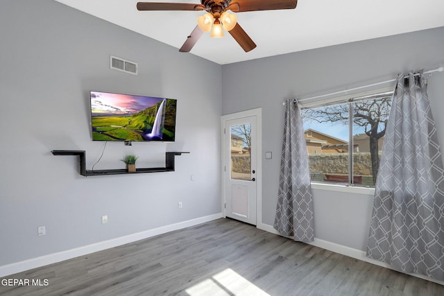 interior space featuring visible vents, a ceiling fan, baseboards, and wood finished floors
