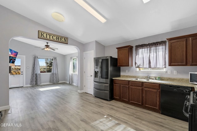 kitchen featuring arched walkways, vaulted ceiling, a sink, stainless steel fridge with ice dispenser, and black dishwasher