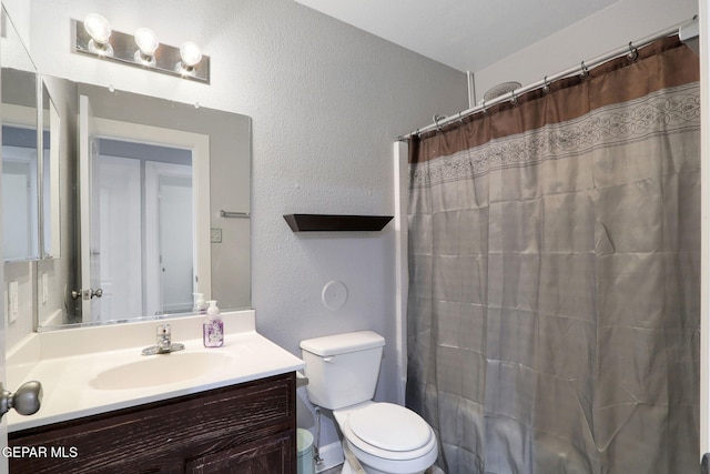 bathroom with vanity, a textured wall, a shower with shower curtain, and toilet