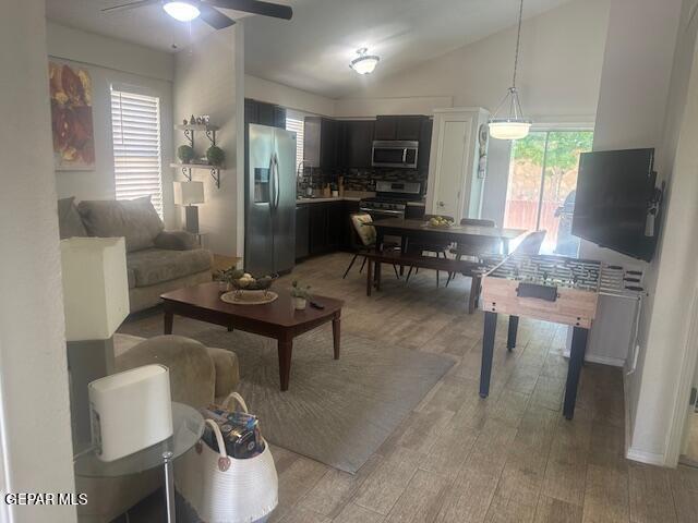 living area featuring light wood-type flooring, a ceiling fan, and vaulted ceiling