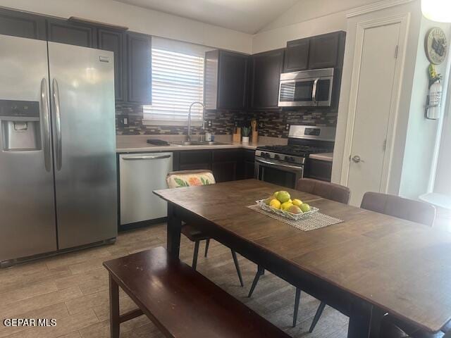 kitchen with a sink, appliances with stainless steel finishes, backsplash, and light countertops