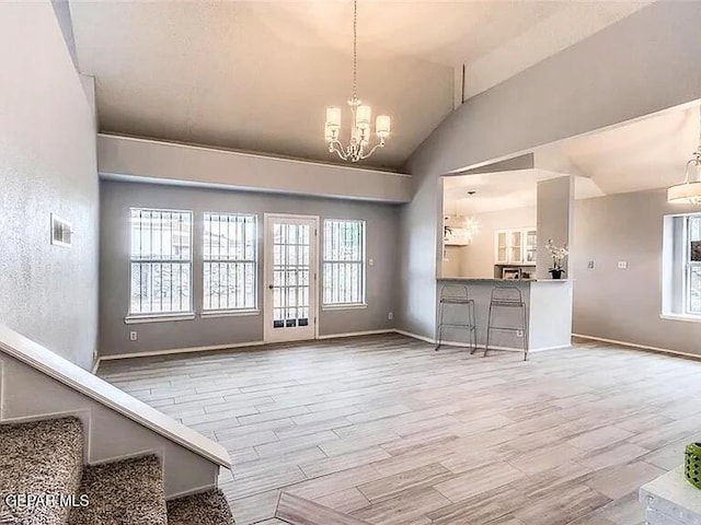 unfurnished dining area with wood finished floors, lofted ceiling, a chandelier, and a healthy amount of sunlight