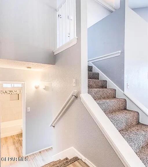 staircase with baseboards and wood finished floors