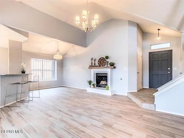 unfurnished living room with baseboards, high vaulted ceiling, an inviting chandelier, and a wealth of natural light