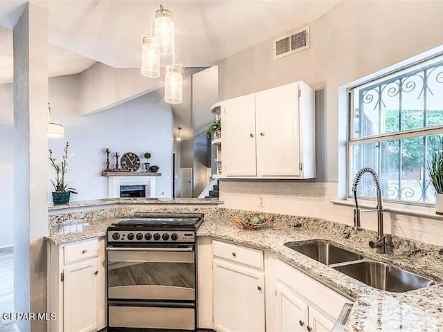 kitchen with visible vents, decorative backsplash, stainless steel gas range oven, white cabinets, and a sink