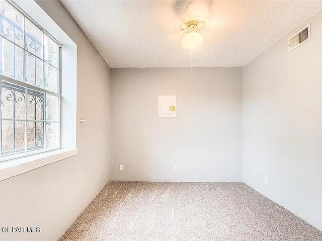 carpeted spare room featuring a textured ceiling and visible vents