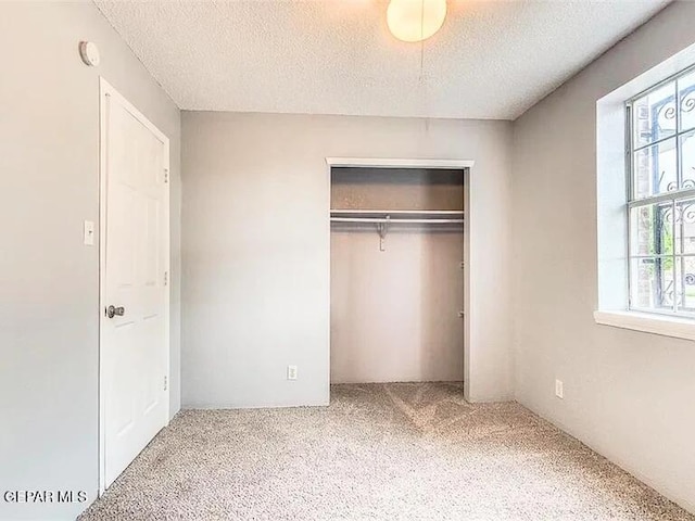 unfurnished bedroom featuring a textured ceiling, carpet, and a closet