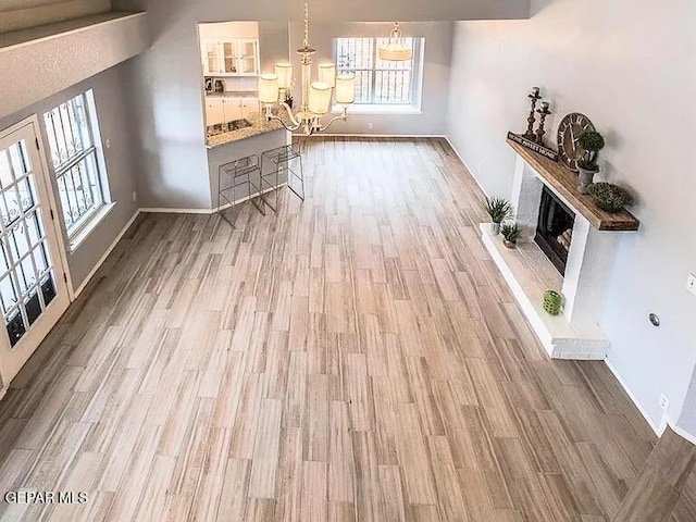 living area with a fireplace with raised hearth, baseboards, a wealth of natural light, and wood finished floors