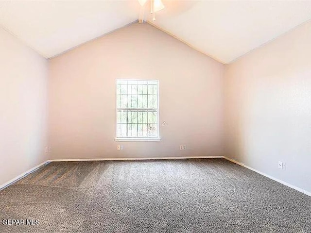 empty room featuring baseboards, ceiling fan, carpet, and vaulted ceiling