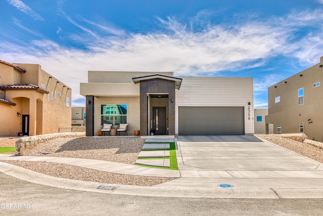 view of front facade with an attached garage, concrete driveway, and stucco siding