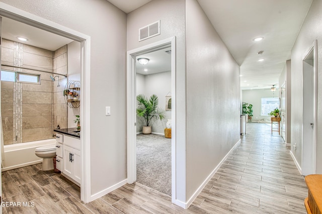 hall with light wood-style floors, baseboards, and visible vents